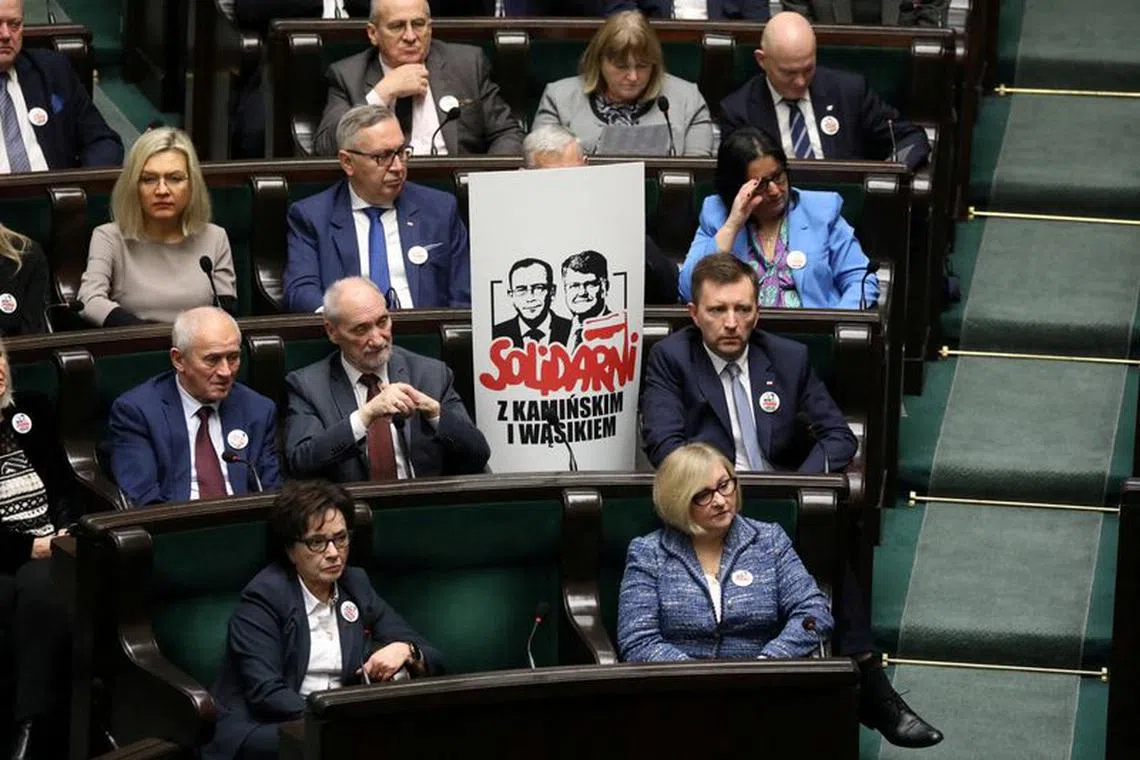 FILE PHOTO: Polish members of parliament from the Law and Justice (PiS) party sit next to a poster with images of former Interior Minister Mariusz Kaminski and his deputy Maciej Wasik, during a parliamentary session in Warsaw, Poland, January 16, 2024. Agencja Wyborcza.pl via REUTERS/File Photo