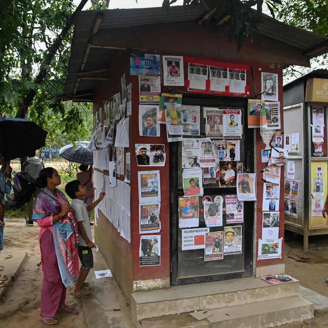 Family members check photographs of missing people pasted on a bank ATM near Trishuli camp in the aftermath of flash floods in Nepal’s Nuwakot district on Sept 5.