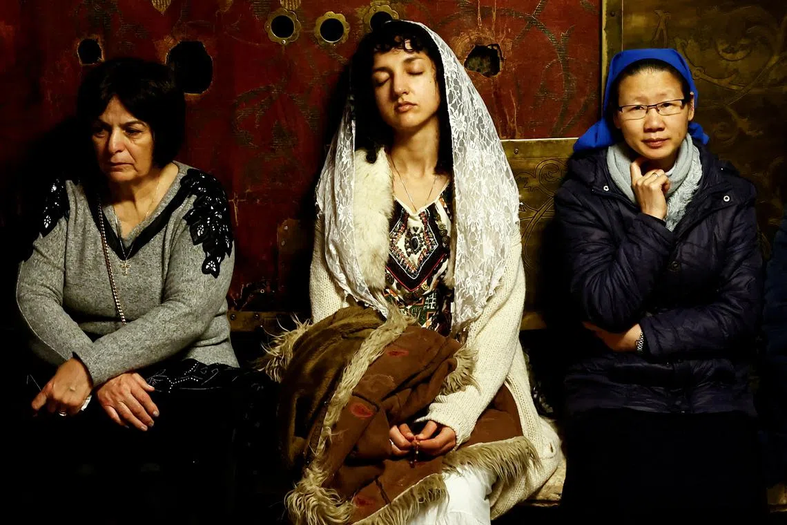 A worshipper praying near the star which marks the spot believed to be the exact birthplace of Jesus, in the Grotto at the Church of the Nativity, in Bethlehem, in the Israeli-occupied West Bank, Dec 25, 2023.