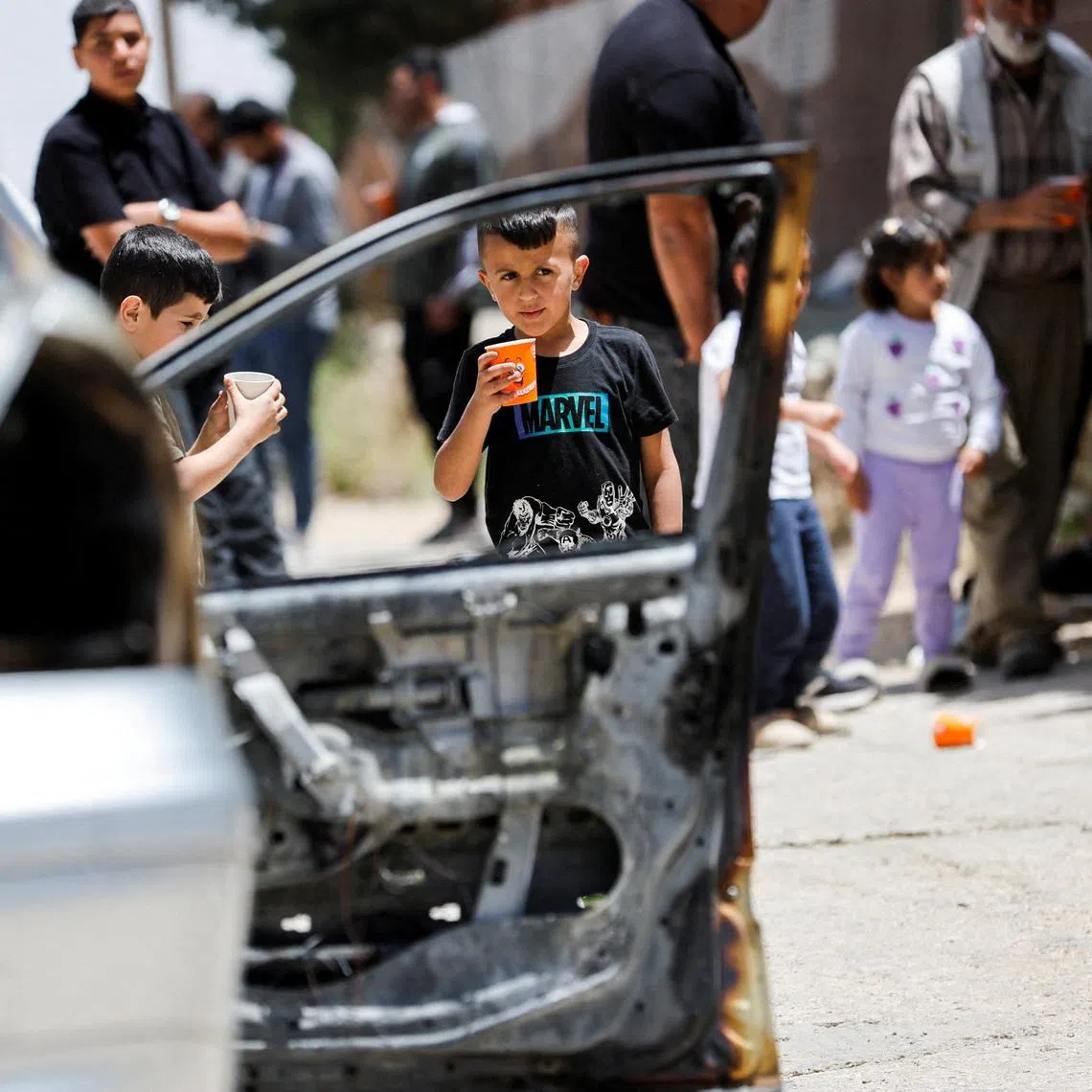 FILE PHOTO: Children stand near a damaged car, which Palestinians say was burned by Israeli settlers,in Halhul near Hebron in the Israeli-occupied West Bank May 20,2026. REUTERS/Mussa Qawasma/File Photo