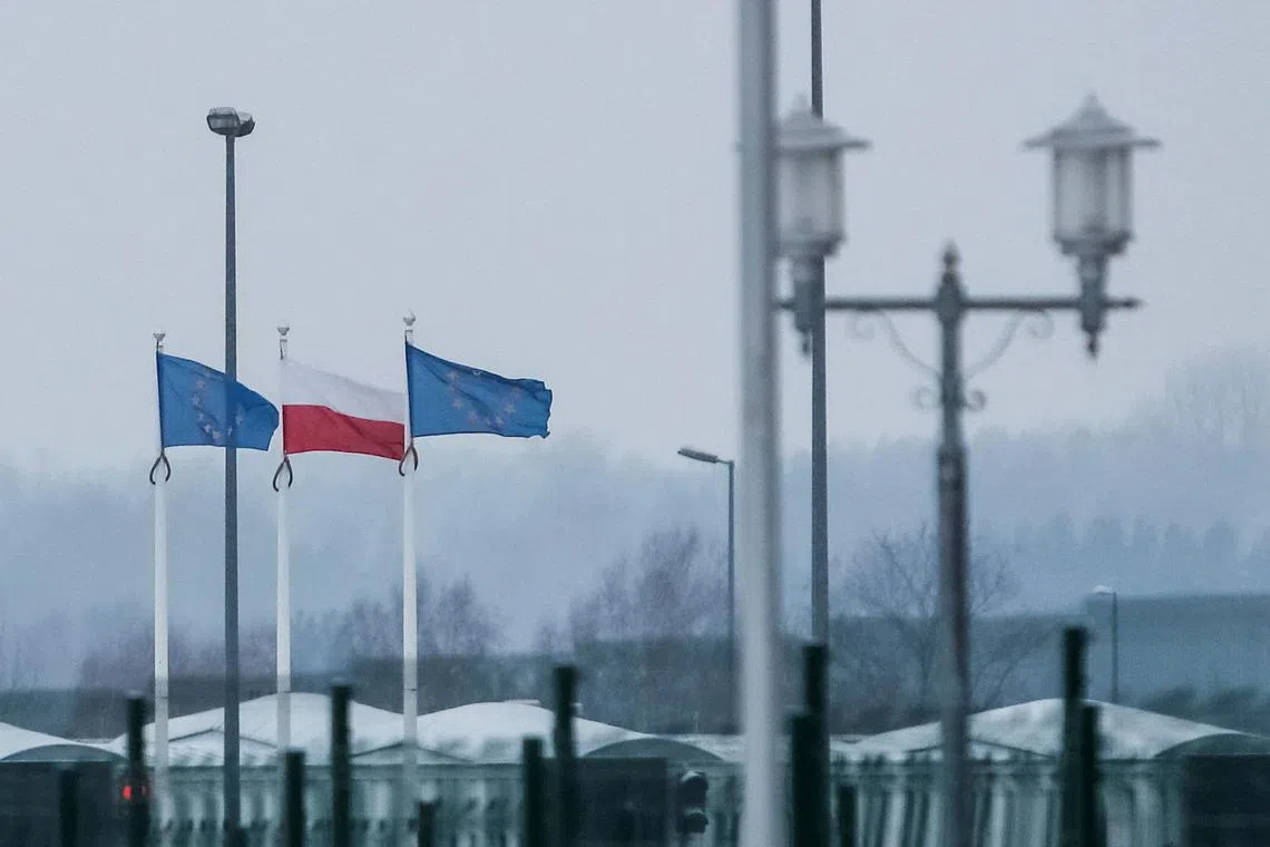 A view from Belarus' side of the frontier with Poland shows Polish and EU flags behind a fence at the Bruzgi-Kuznica checkpoint.