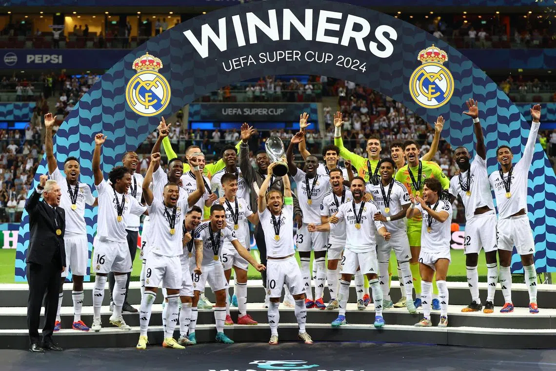 Luka Modric lifts the trophy as Real Madrid players celebrate winning the Uefa Super Cup.