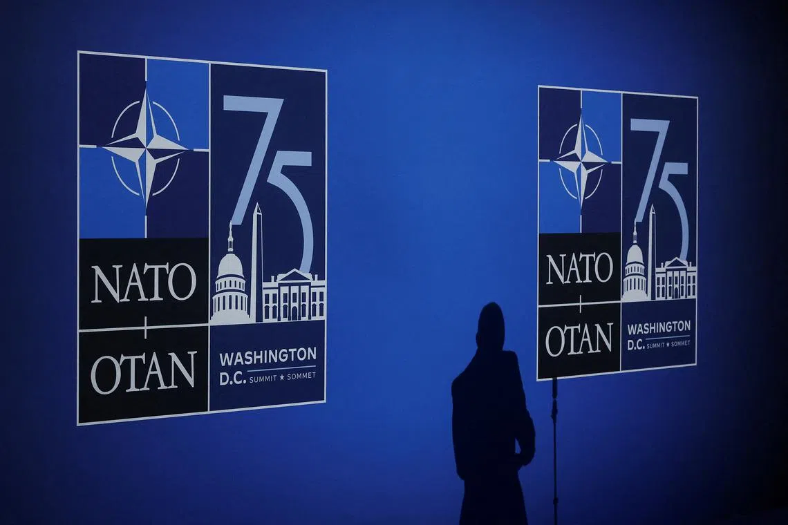 FILE PHOTO: A journalist casts a shadow next to logos on the day of the NATO 75th Anniversary celebratory event in Washington, U.S., July 9, 2024. REUTERS/Yves Herman/File Photo