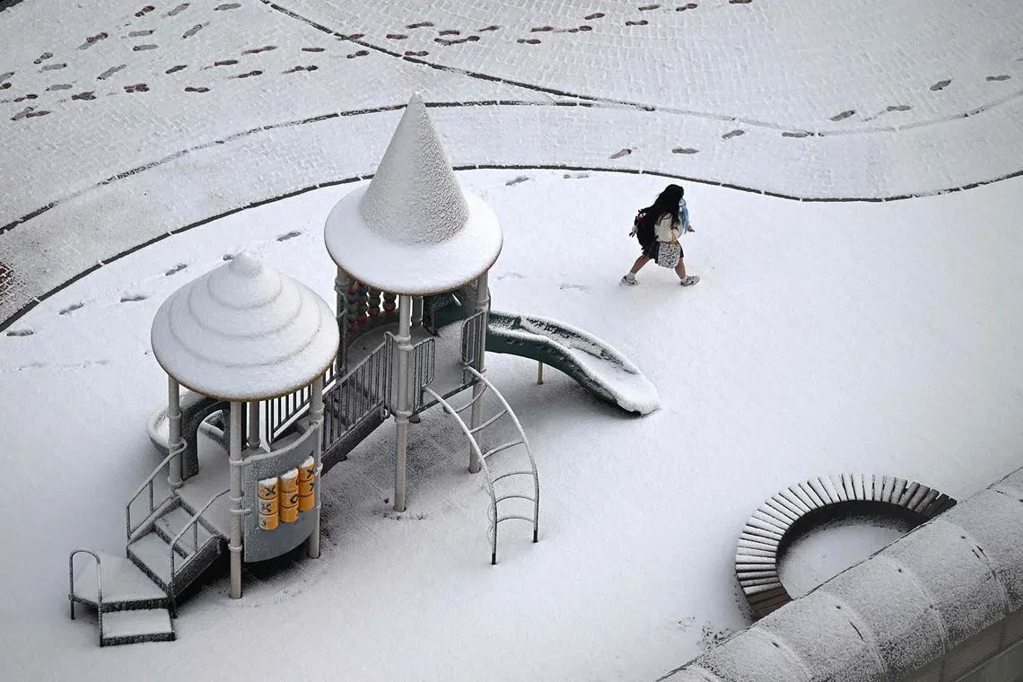 A student walking across a snow-covered playground after snowfall in Goyang, South Korea, on Nov 27, 2024. 