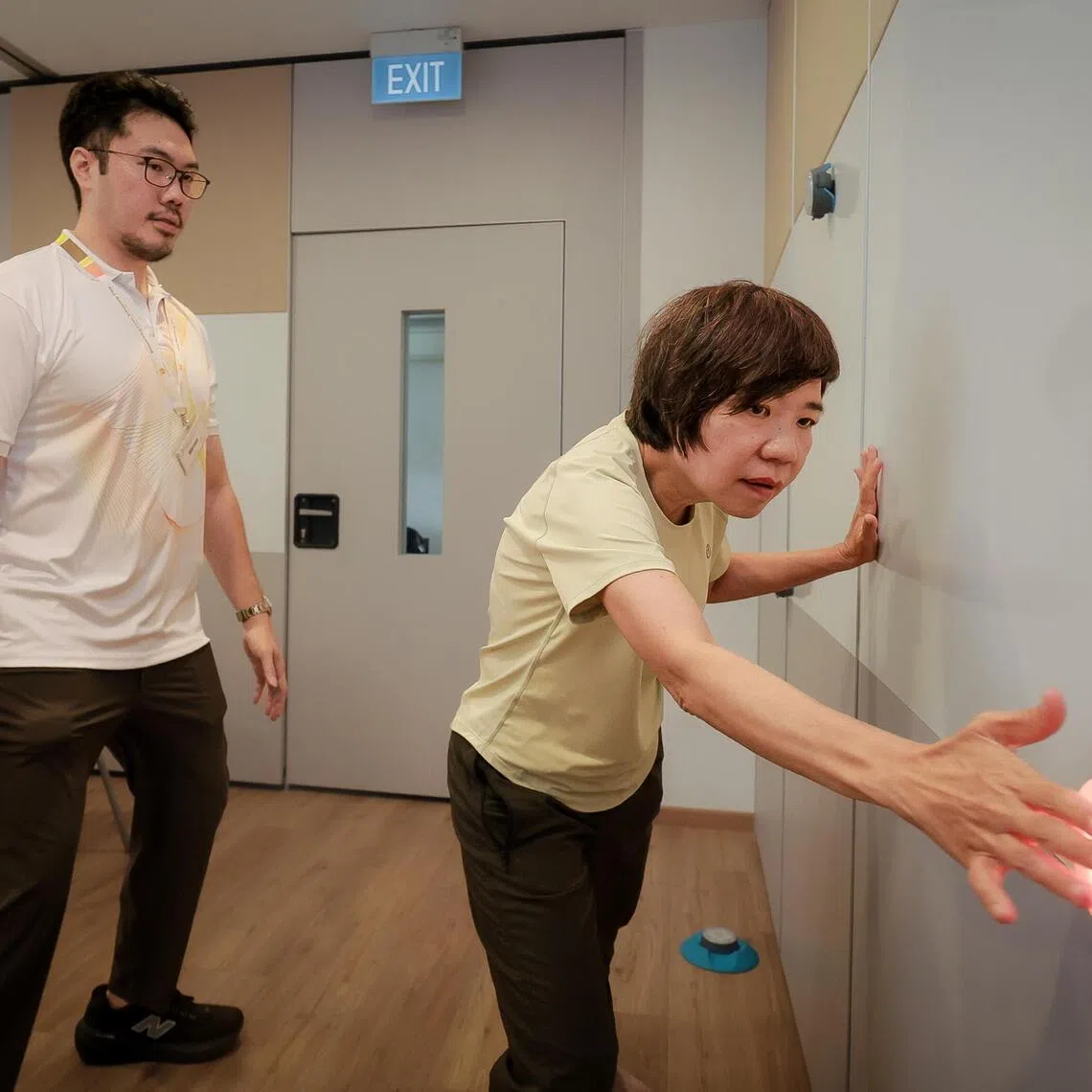 Physiotherapist Marcus Tan assists Parkinson’s disease patient Lim Mui Huang with balance and agility training as part of the KEEP community rehabilitation programme.
