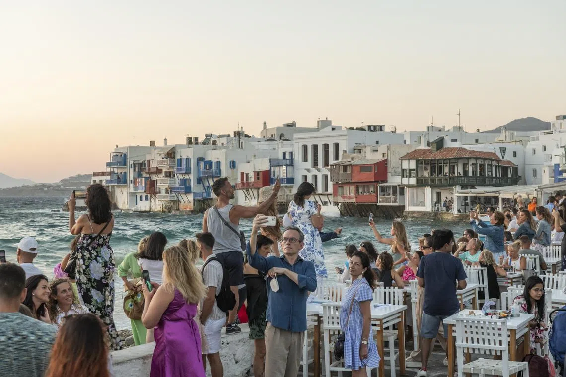 FILE — Crowds gathering for the sunset in Mykonos, Greece, on Aug. 7, 2022. As development alters Greek islands’ nature and culture, the locals push back. (Maria Mavropoulou/The New York Times)