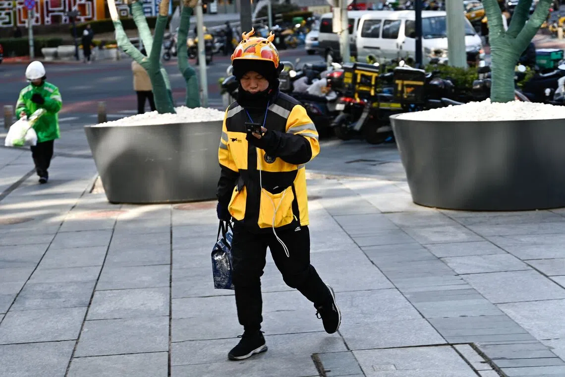 A food delivery man works in Beijing on February 17, 2025. (Photo by Pedro PARDO / AFP)