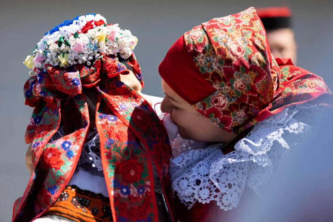 A boy wearing a traditional woman's costume, this year's "King", is kissed by his mother, during traditional folklore festival "Ride of the Kings", in Vlcnov, Czech Republic, on May 25, 2025. 