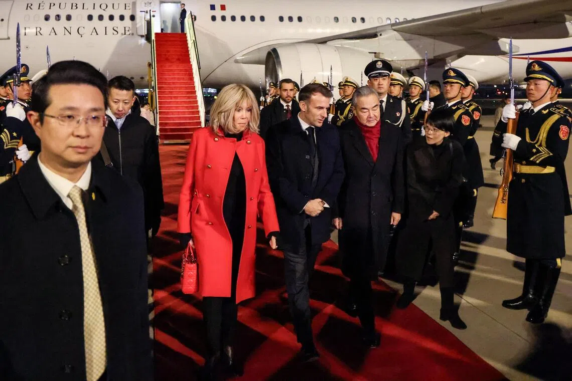Chinese Foreign Minister Wang Yi receiving French President Emmanuel Macron and his wife Brigitte at Beijing’s airport on Dec 3. 