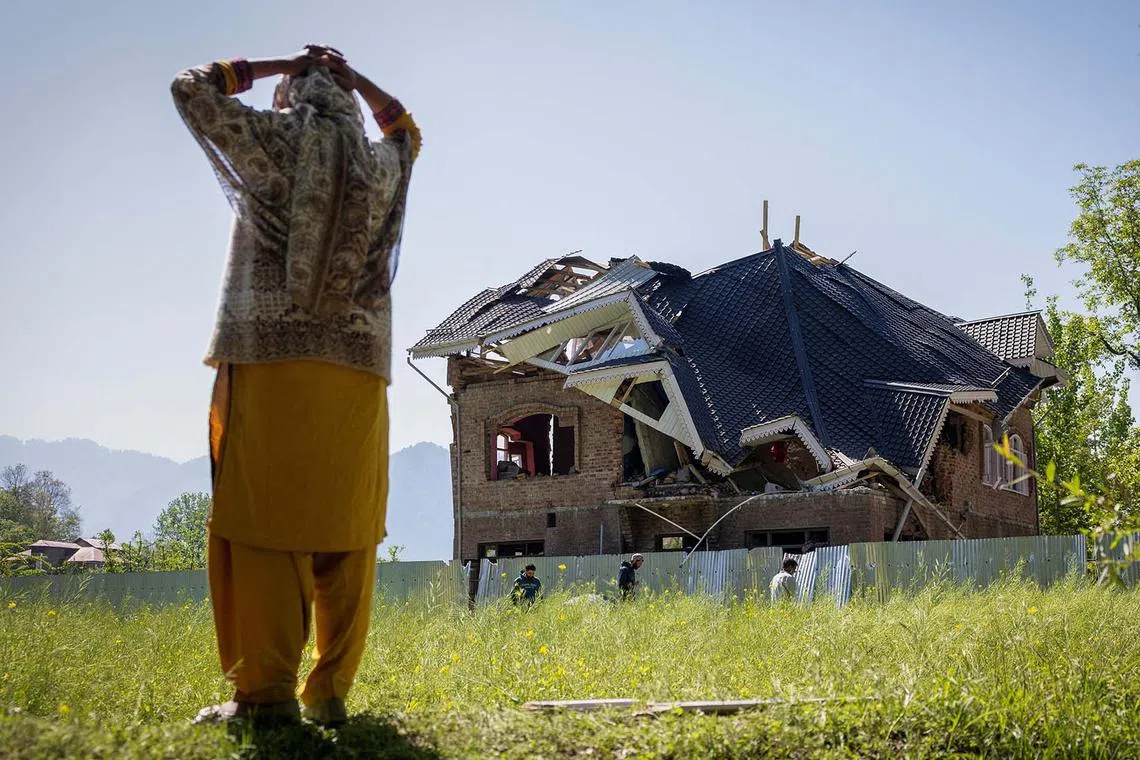A woman standing next to Amir Nazir Wani's family house, which was destroyed by the Indian authorities, in Khasipora village in Tral, south Kashmir, April 27, 2025. 