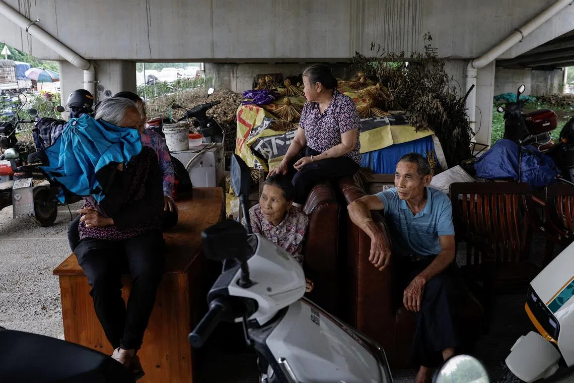 Residents from flood affected area sitting at an underpass with their furniture that were moved from their houses, following heavy rainfall at a village, in Qingyuan, Guangdong province, China, on April 22, 2024. 