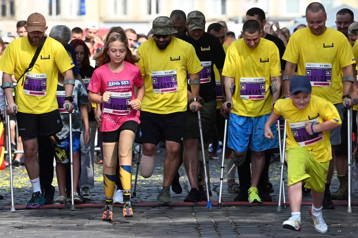 Yana Stepanenko (second left) and Ukrainian servicemen who lost their limbs taking part in a half marathon in Lviv, Ukraine, on Sept 3.