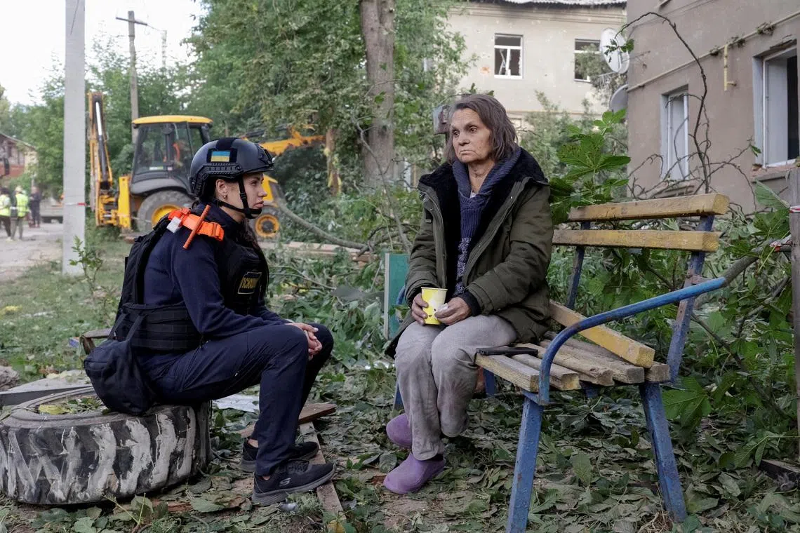 An emergency psychologist talks to a resident at the site of an apartment building hit by a Russian air strike, amid Russia's attack on Ukraine, in Kharkiv, Ukraine June 20, 2026. REUTERS/Sofiia Gatilova