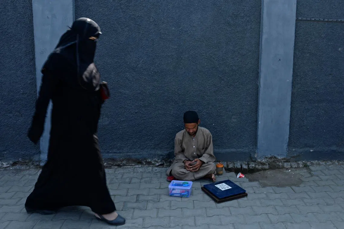 A man with a scale waits for customers along a street in Srinagar on September 29, 2022.
