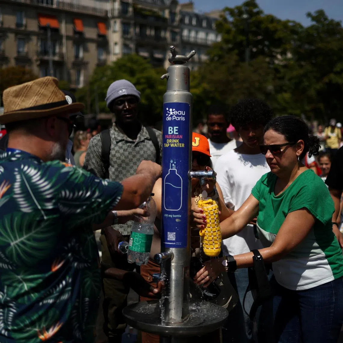 People refill water bottles from a public fountain near the Place du Trocadero in Paris on June 27.