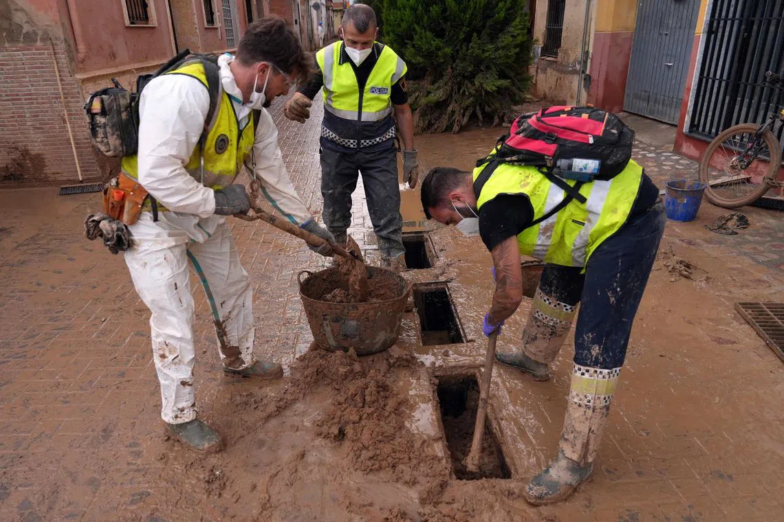 Local police officers removing mud to unclog drains in Catarroja, Valencia, on Nov 8.