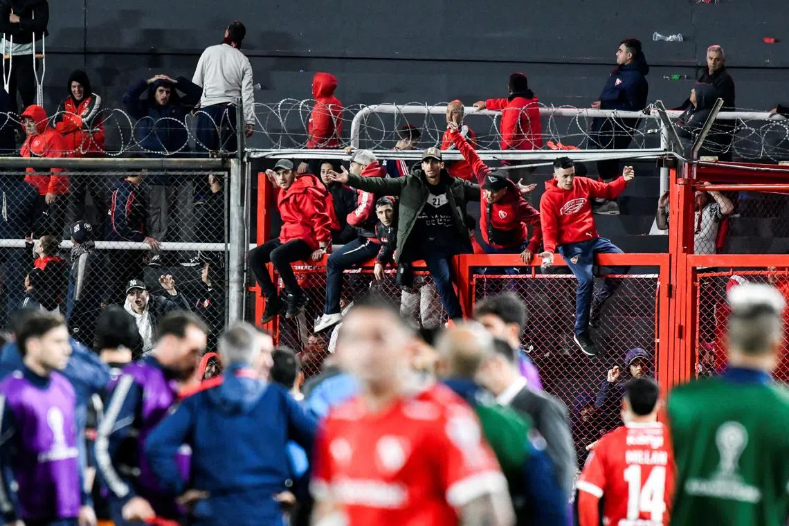 FILE PHOTO: Independiente supporters climb onto stadium gates, urging police and local security to intervene in the Chile fans' area to stop them from throwing objects, before clashes broke out at the second leg of the Copa Sudamericana Round of 16 match, which was suspended due to violence in the stands, with the Chilean side leading on aggregate, in Avellaneda, Argentina August 20, 2025. REUTERS/Facundo Morales/File Photo