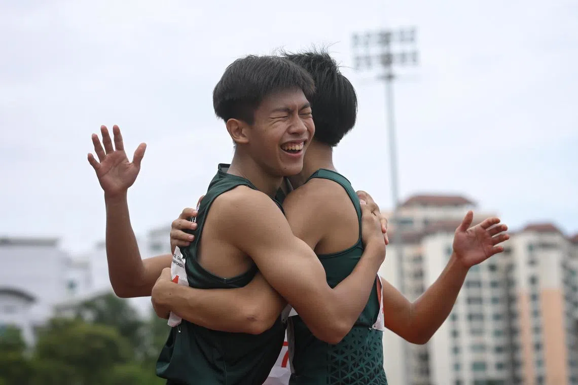 Raffles Institution's Garrett Chua (left) embraces teammate Daryen Ko after their one-two finish in the B Division boys' hurdles final.