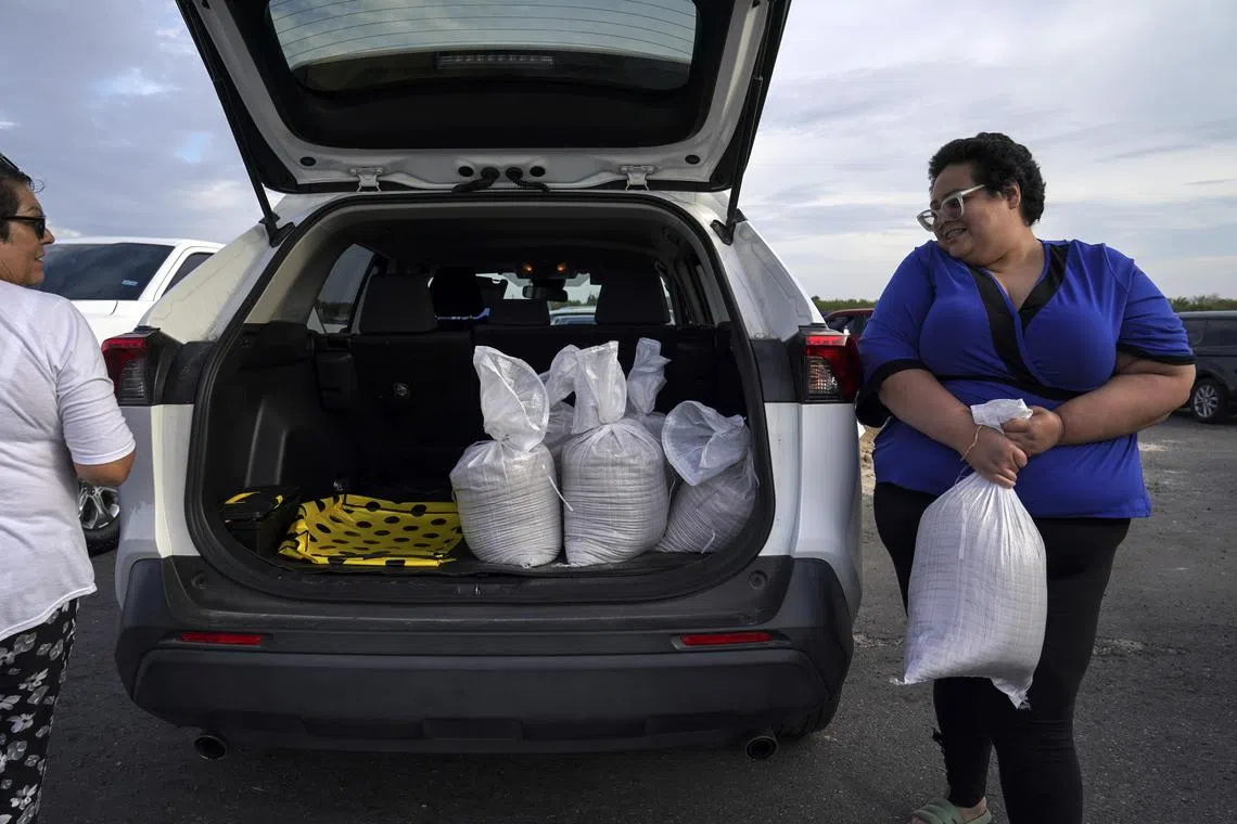 Texas resident Jacklyn Alvarez loads her car with sandbags in preparation for Tropical Storm Harold.