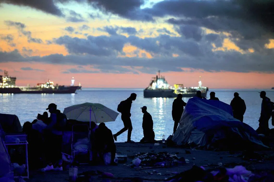 TOPSHOT - Migrants await removal by Spanish police from the temporary makeshift El Guano camp near the Trampolin beach in Spain's north African enclave of Ceuta on October 11, 2026. Migrants were taken by bus to the border area to undergo registration and identification at a reception facility and some of them chose to return voluntarily to Morocco. Spain's King Felipe VI and Queen Letizia are scheduled to visit Ceuta on October 13 where hundreds of migrants remain since the massive influx of tens of thousands of migrants from Morocco in late July, fueling tension in this Spanish North African enclave of some 80,000 inhabitants. (Photo by Thomas COEX / AFP)