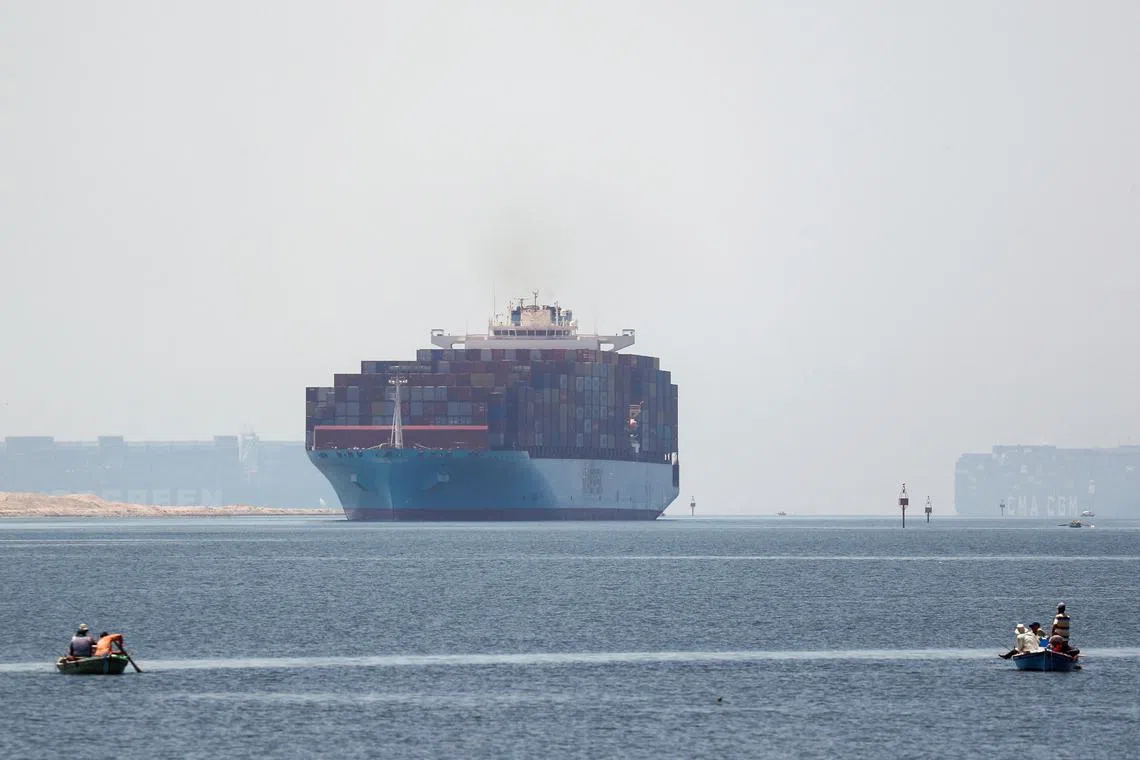 FILE PHOTO: Fishermen travel on boats front of container ships passing through the Suez Canal in Ismailia, Egypt July 7, 2021. Picture taken July 7, 2021. REUTERS/Amr Abdallah Dalsh/File Photo