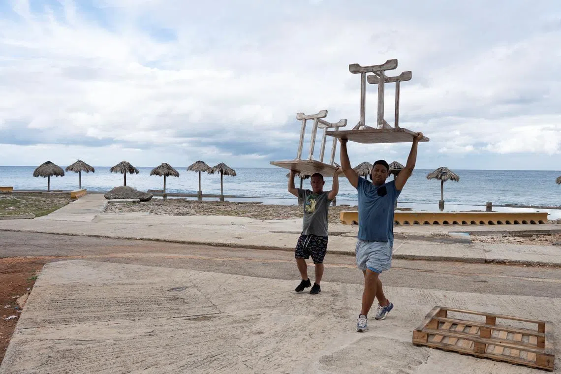 Men relocate furniture from a restaurant prior to the arrival of Tropical Storm Rafael in Havana, Cuba, November 5, 2024. REUTERS/Alexandre Meneghini