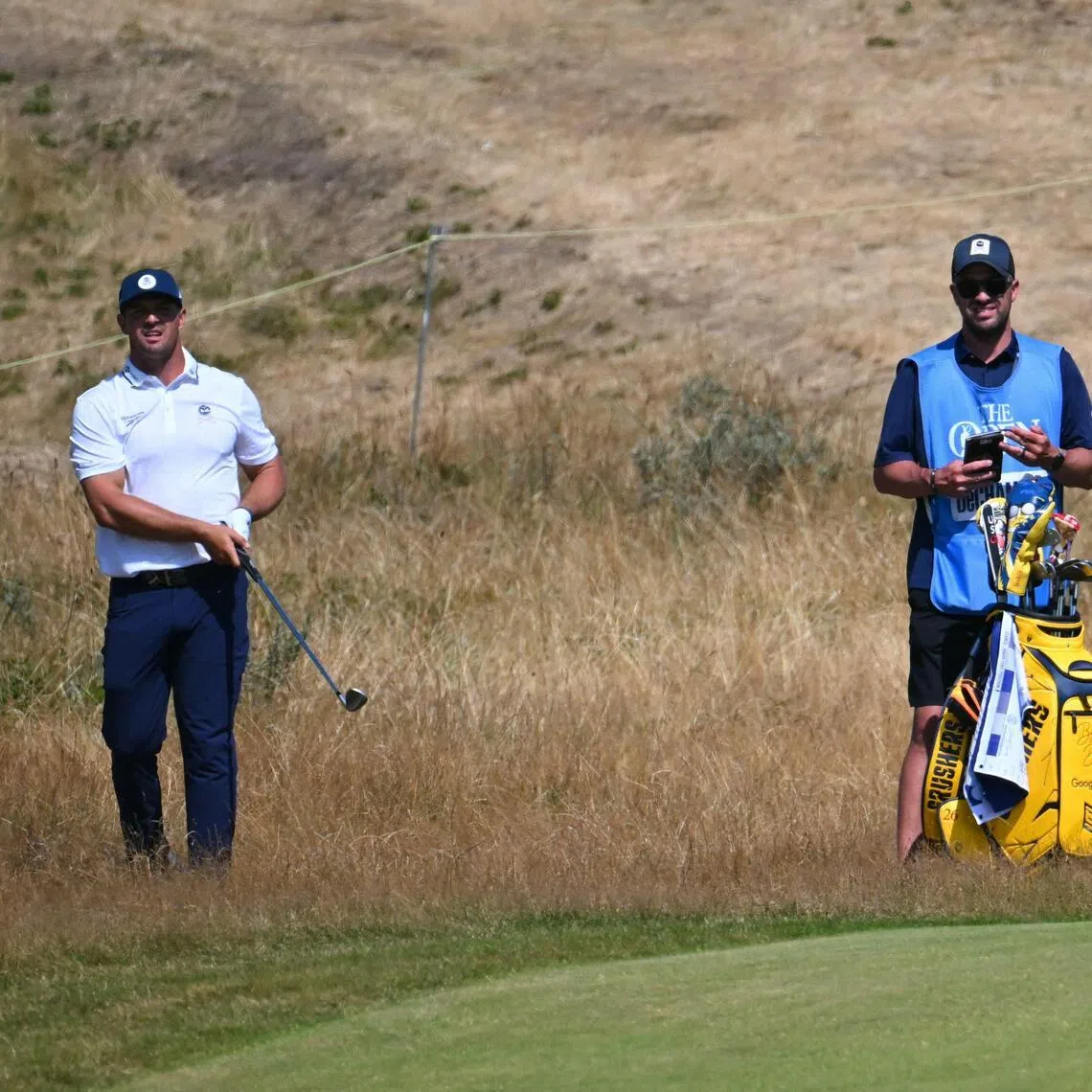 US golfer Bryson DeChambeau (left) and caddie Greg Bodine standing in the rough on the 16th hole during practice for the 154th Open Golf championship at Royal Birkdale Golf Club on July 13.