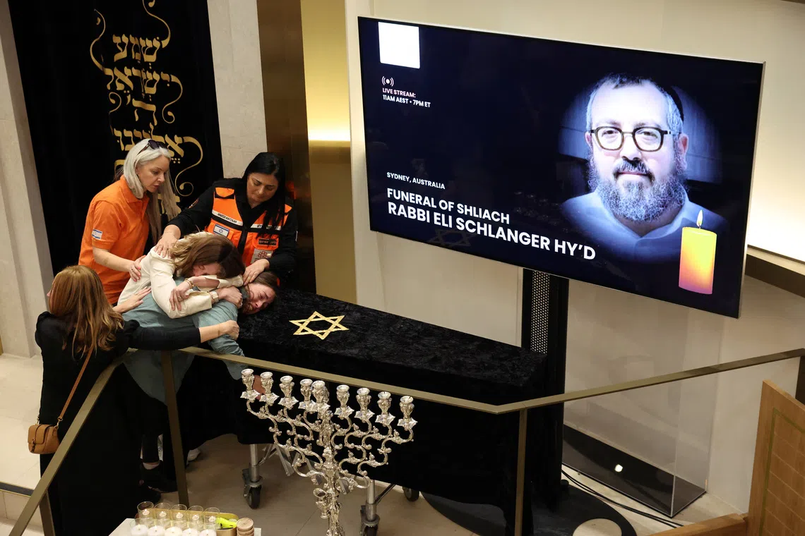 Family members of Rabbi Eli Schlanger, who was killed during a shooting at a Jewish Hanukkah celebration at Sydney's Bondi Beach on Sunday, react as they lean over his casket during a funeral at Chabad of Bondi, in Sydney, Australia, December 17, 2025. REUTERS/Hollie Adams/Pool