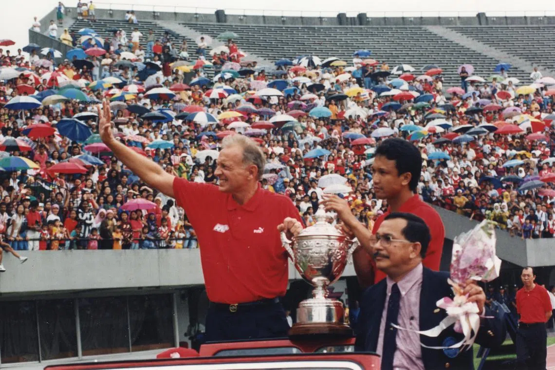 Singapore soccer coach Douglas Moore, captain Fandi Ahmad and team manager Omar Ibrahim acknowledging the cheers as they parade the Malaysia Cup before screaming fans who turned up at the National Stadium to welcome the team home, 18 December 1994.