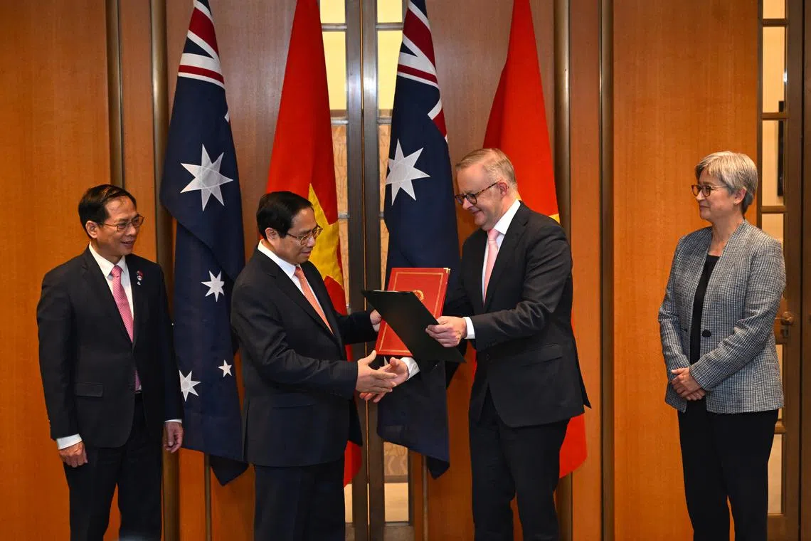 Australian Prime Minister Anthony Albanese (right) and Vietnamese Prime Minister Pham Minh Chinh (left) exchange documents during a signing ceremony at Parliament House in Canberra.