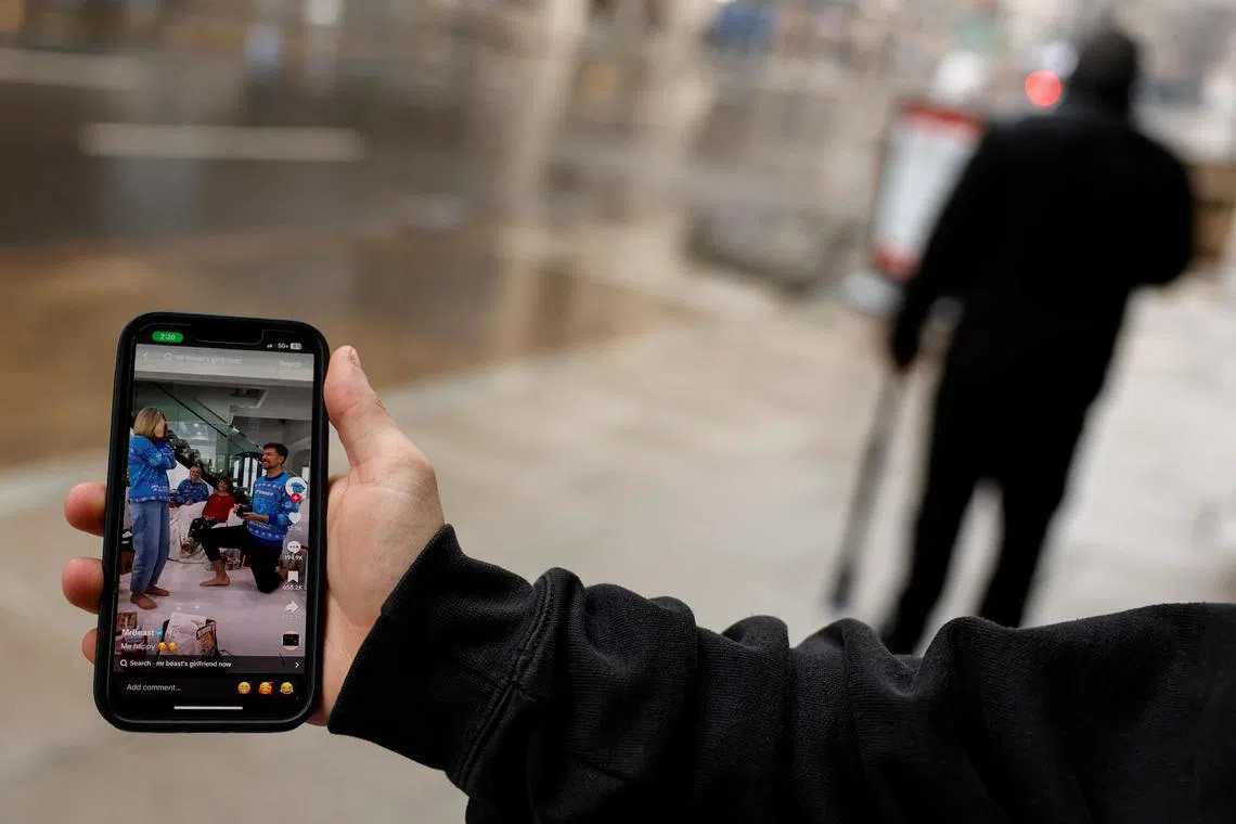 A man poses with his smartphone displaying the TikTok page of MrBeast in Washington.