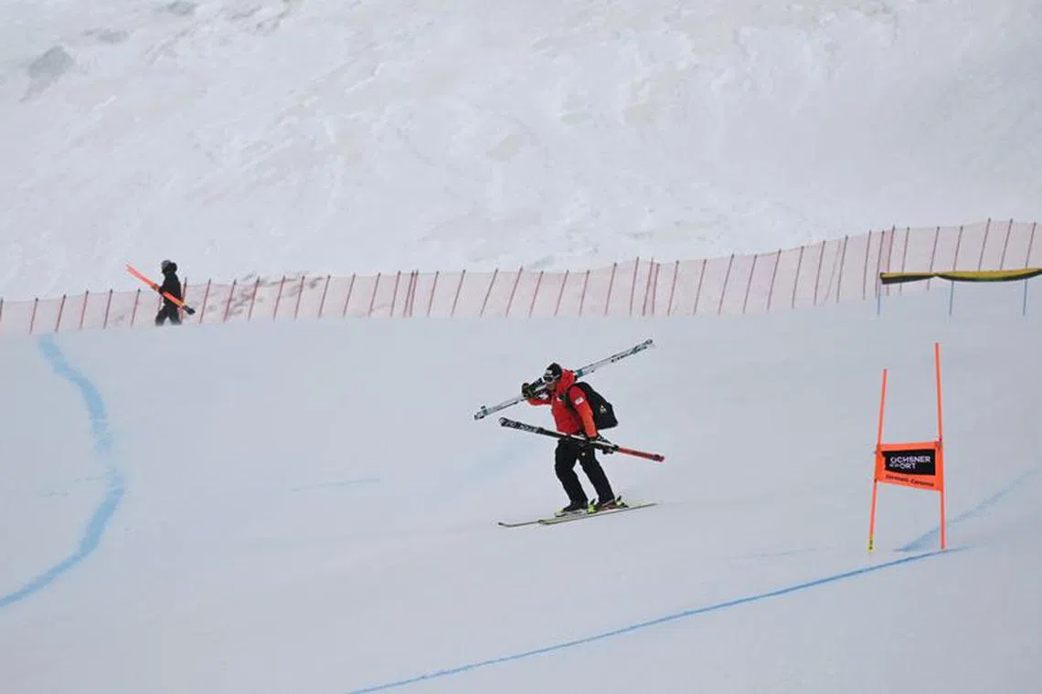 Alpine Skiing - FIS Alpine Ski World Cup - Women's Downhill - Cervinia, Italy - November 19, 2023 A person is seen carrying skis after the women's downhill race is cancelled due to strong winds REUTERS/Angelika Warmuth