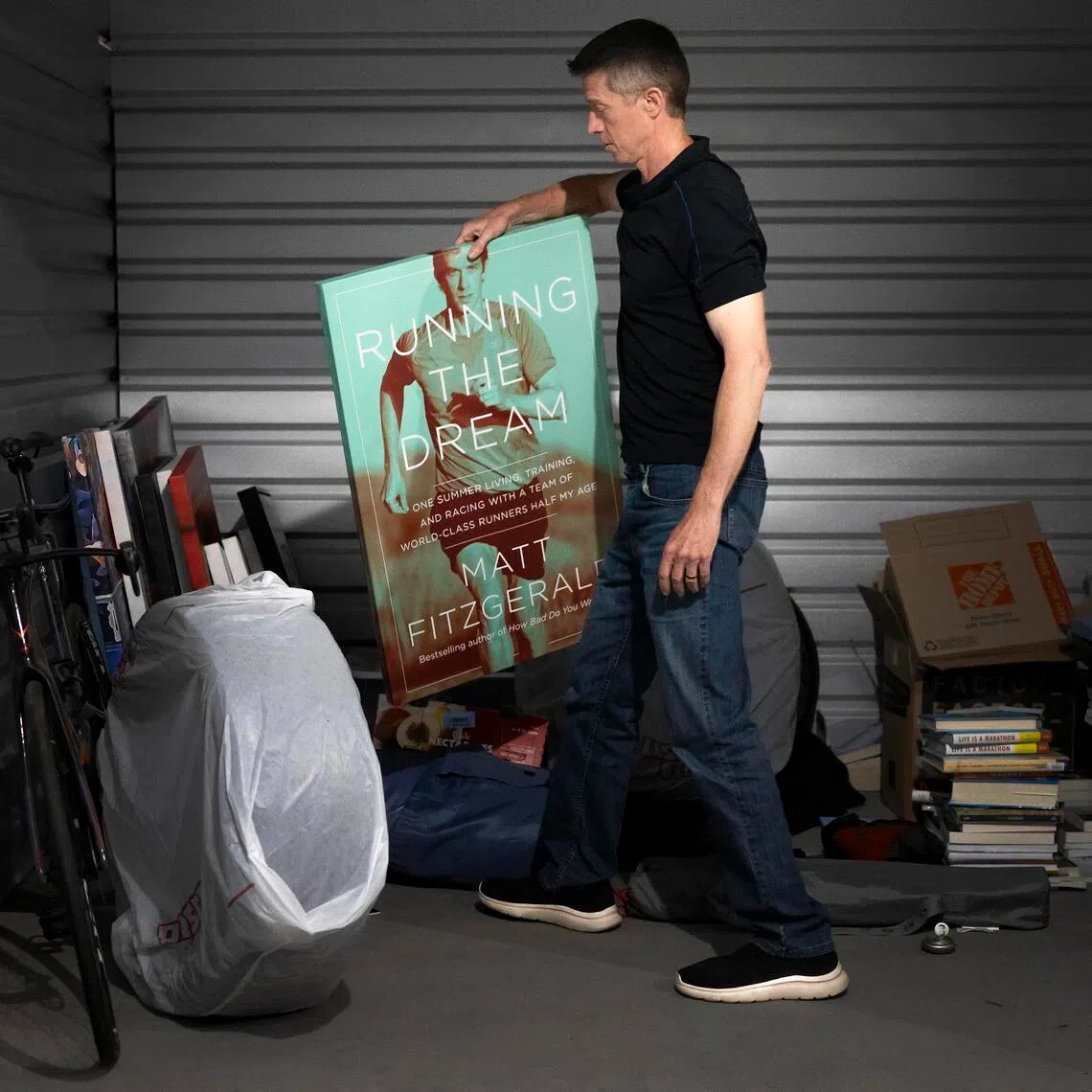 Matt Fitzgerald holds a poster of the cover for his book, Running The Dream, at his storage unit in Flagstaff, Arizona, on June 28.