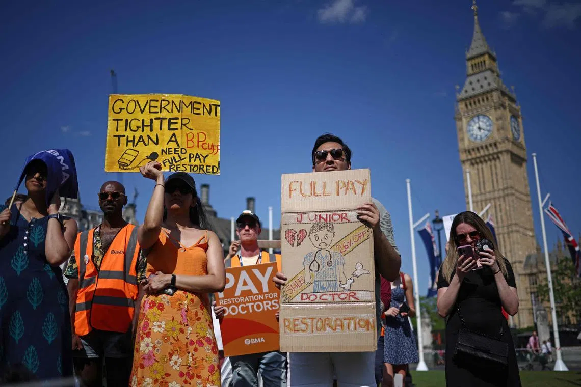 Demonstrators hold up placards as they take part in a protest by so-called 'junior doctors', physicians who are not senior specialists but who may have years of experience, in Parliament Square in central London, on June 16, 2023, during their on-going dispute with the government over over pay and working conditions. (Photo by HENRY NICHOLLS / AFP)