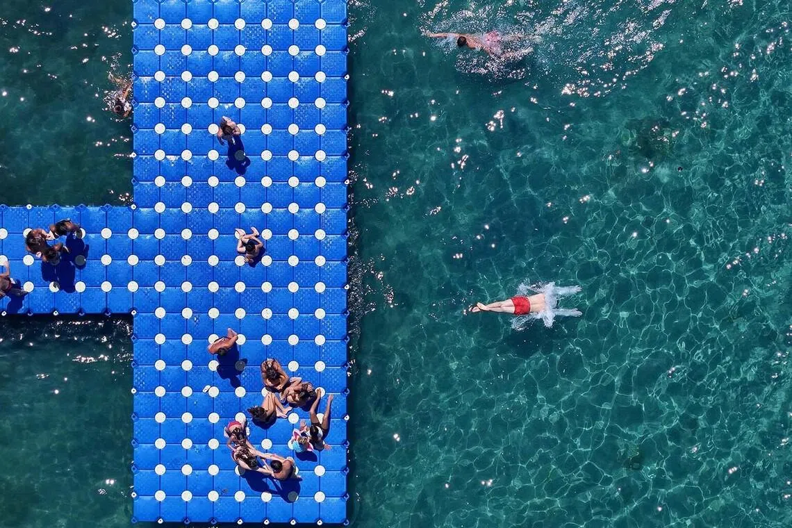 TOPSHOT - This aerial photograph shows beachgoers on an artifical pier in Durres, western Albania, on June 29, 2026. Europe's deadly heatwave pushed east with hundreds of millions still sweltering across the continent despite fleeting relief from overnight storms, notably in France and Belgium. (Photo by Adnan Beci / AFP)