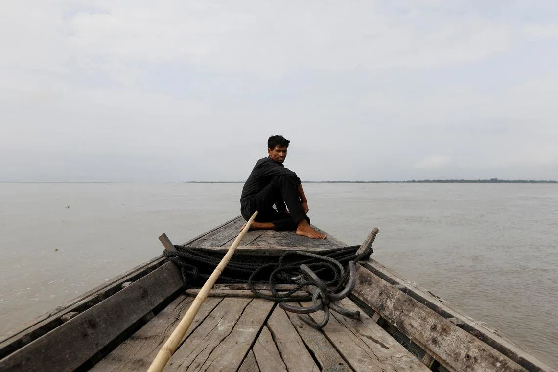 FILE PHOTO: A man sits in a boat on the waters of the Brahmaputra river near the international border between India and Bangladesh in Dhubri district, in the northeastern state of Assam, India August 4, 2018.  REUTERS/Adnan Abidi/File Photo