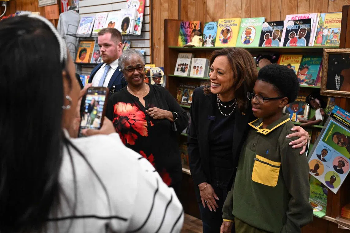 Ms Harris poses for a photo with a young customer as she visits Hakim's Bookstore & Gift Shop in the West Philadelphia neighbourhood of Philadelphia.