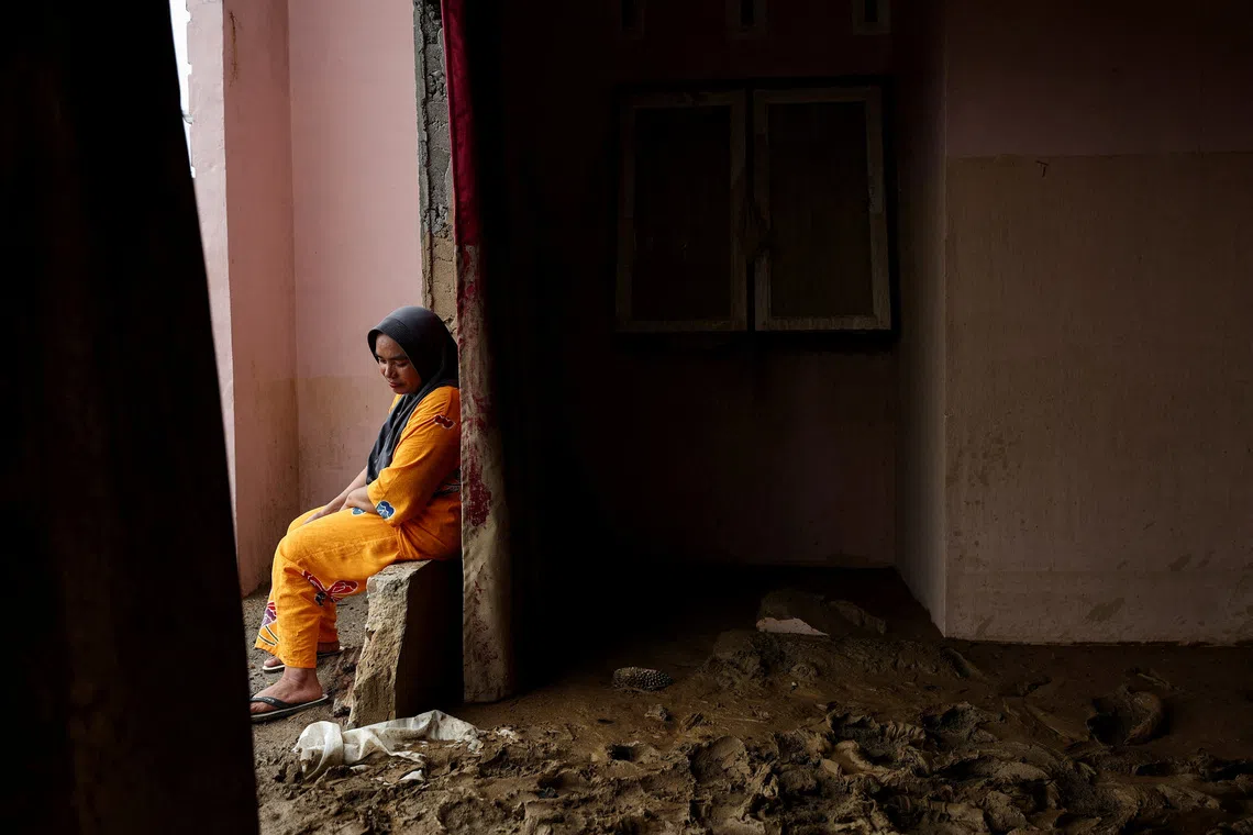 A woman sitting outside her damaged house following a deadly flash flood in Batang Toru, South Tapanuli, North Sumatra province, Indonesia, Dec 7, 2025.