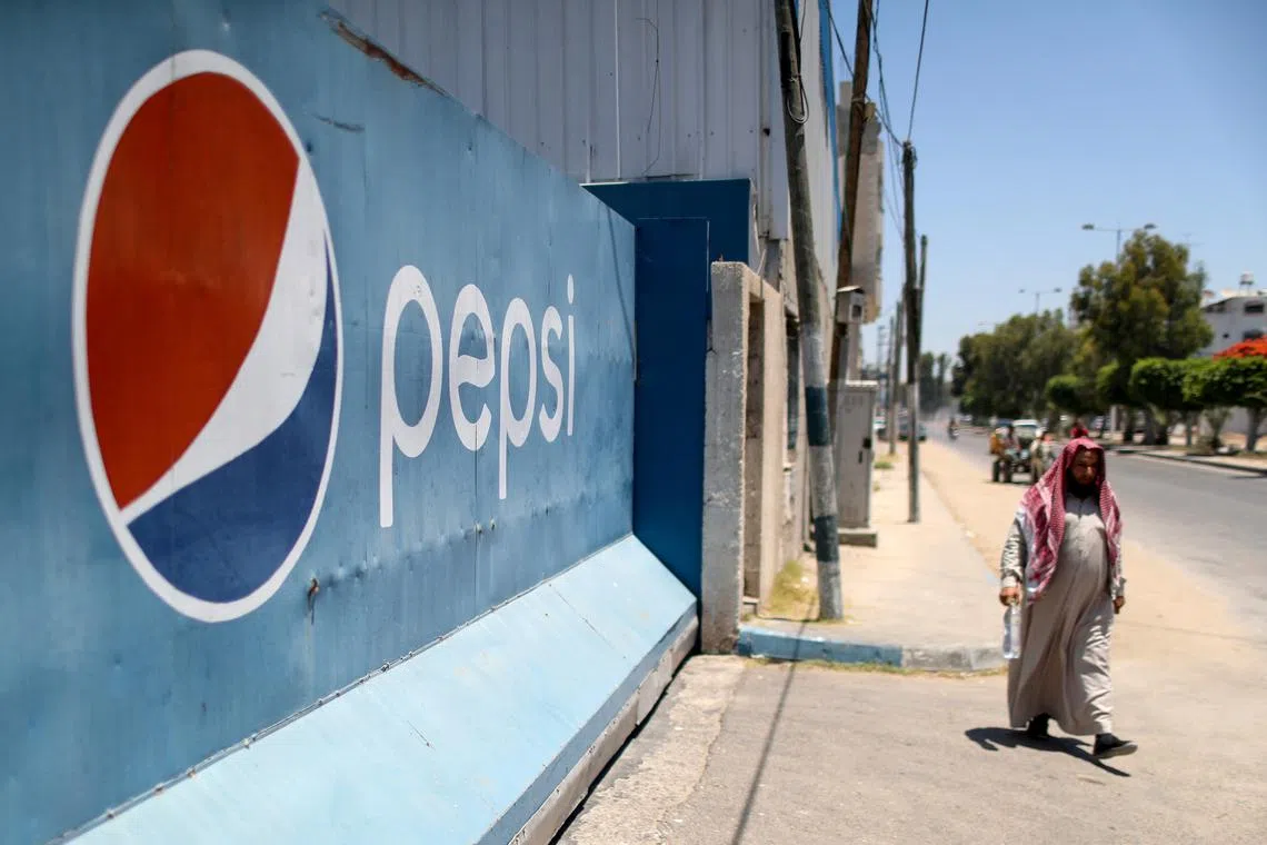 FILE PHOTO: A Palestinian man walks past Gaza Pepsi factory for soft drinks in Gaza City June 21, 2021. REUTERS/Mohammed Salem/File Photo