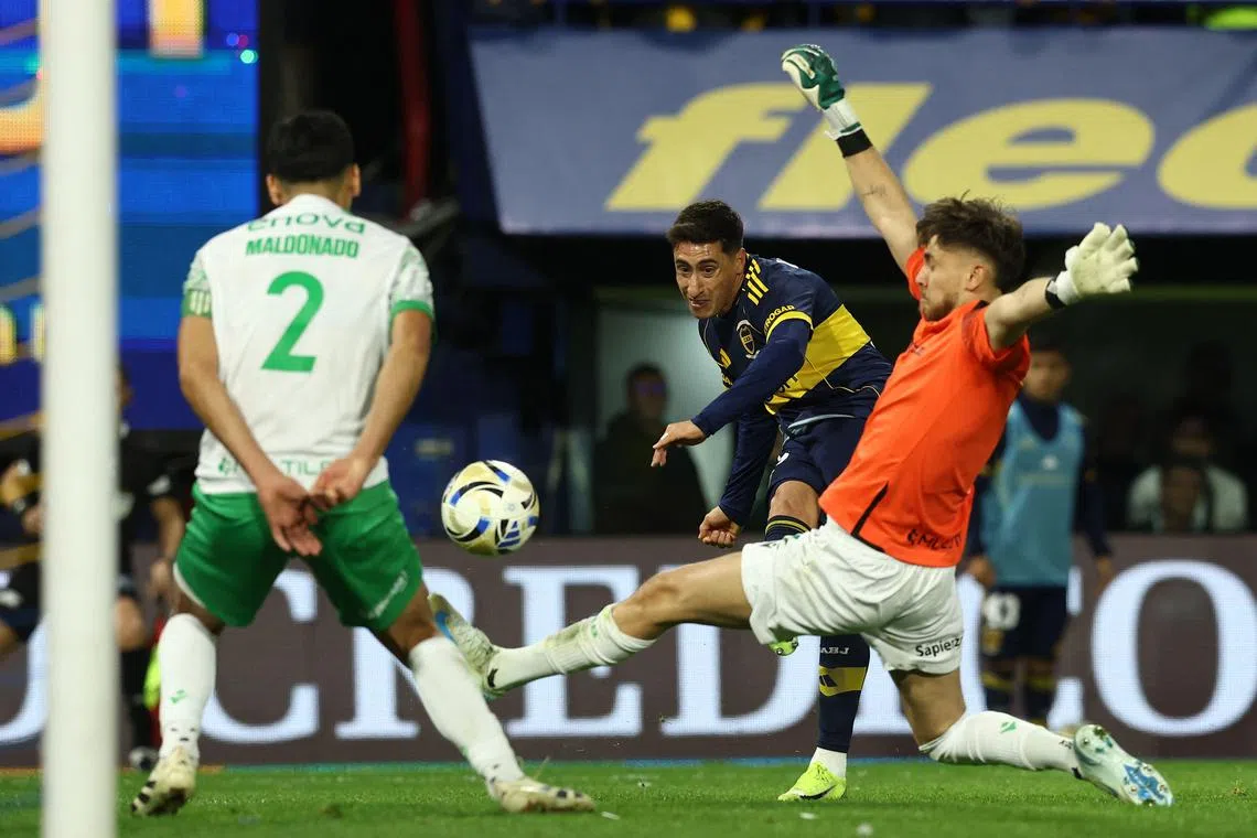 Boca Juniors' Uruguayan forward Miguel Merentiel shooting past Banfield's goalkeeper Facundo Sanguinetti as defender Alexis Maldonado tries to block in the Argentine Professional Football League 2025 Clausura Tournament match at La Bombonera Stadium in Buenos Aires on Aug 24, 2025.