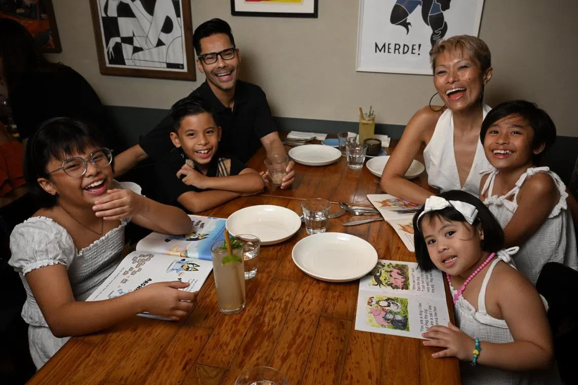 Ms Nichol Ng with her husband Eddy Taps and their children read books while waiting for their lunch at Artichoke restaurant.