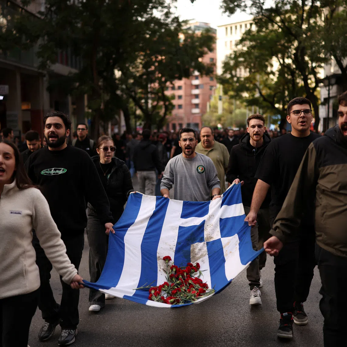 Athens’ Polytechnic students carry a blood-stained Greek flag with red carnations, during a march marking the 52nd anniversary of a 1973 student uprising against the military junta that ruled the country at the time, in Athens, Greece, November 17, 2025. REUTERS/Stelios Misinas