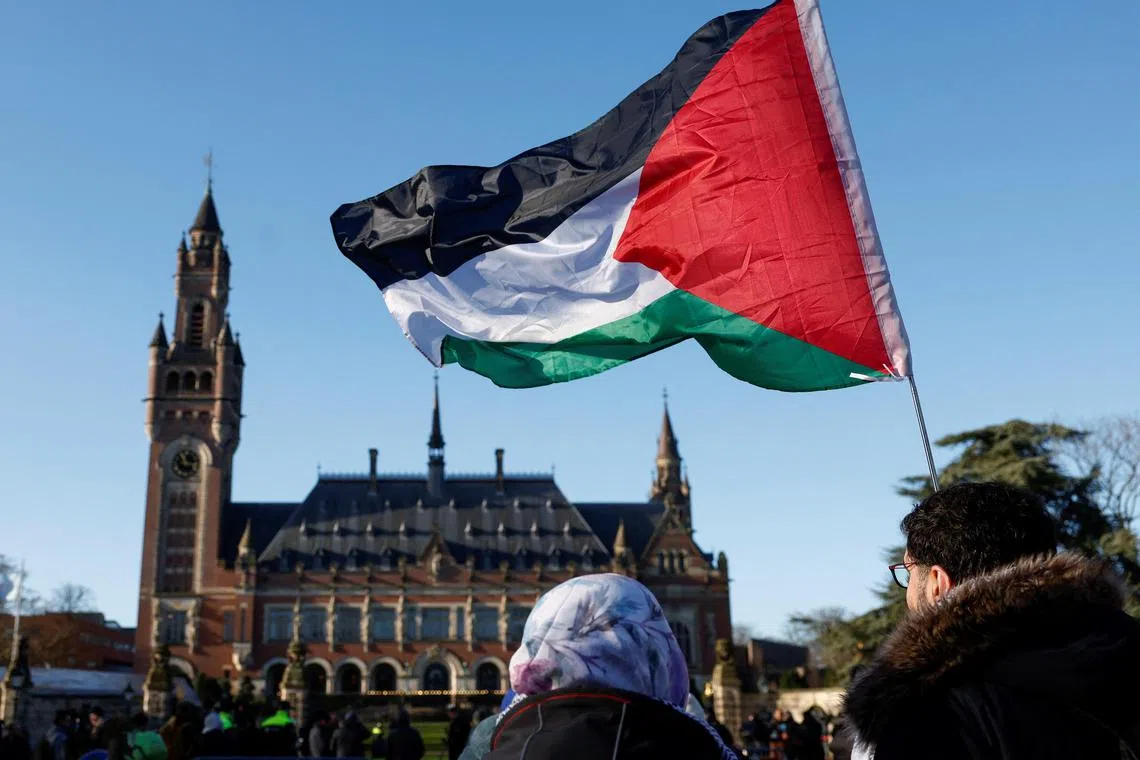 Protesters hold a Palestinian flag outside the International Court of Justice in The Hague, Netherlands, following accusations by South Africa that the Israeli military operation in Gaza is a state-led genocide, on Jan 26.