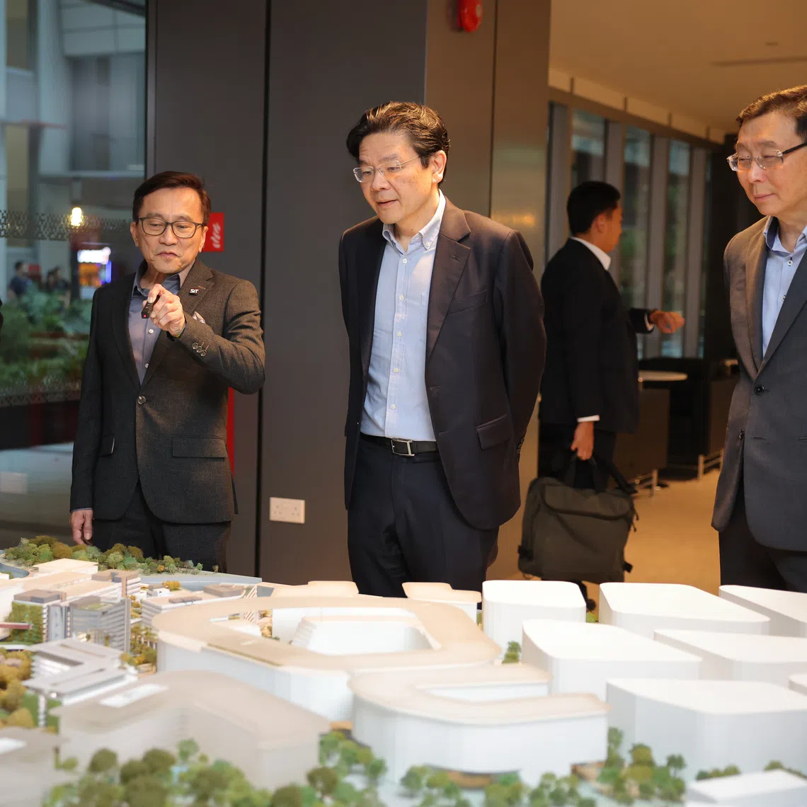 Prime Minister Lawrence Wong (second from right) looking at a model of Singapore Institute of Technology's Punggol campus on Sept 16.