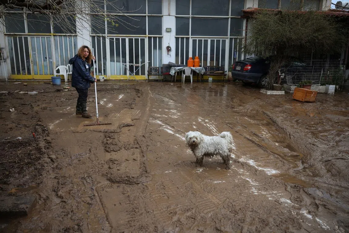 A woman cleans mud from her yard, after heavy rain and gale-force winds battered Greece, leaving flooded houses and the authorities rushing to repair damage, near Rafina, Greece, April 2, 2026. REUTERS/Louisa Gouliamaki