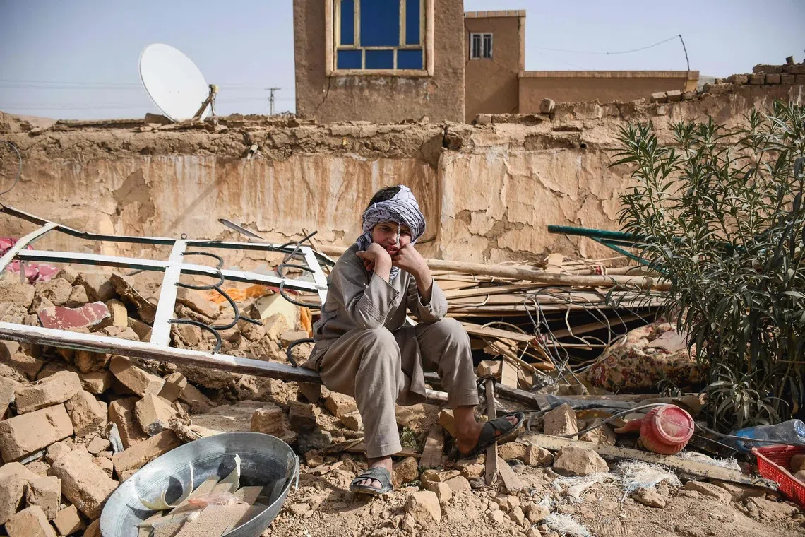 An Afghan earthquake survivor siting over the remains of a damaged house at a village in Tashqurghan, in the Khulm district of Samangan province on Nov 3, 2025. 