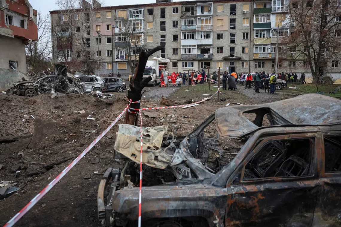 Residents receive humanitarian aid near their apartment building damaged during Russian missile strikes in the Kharkiv region on Nov 17.