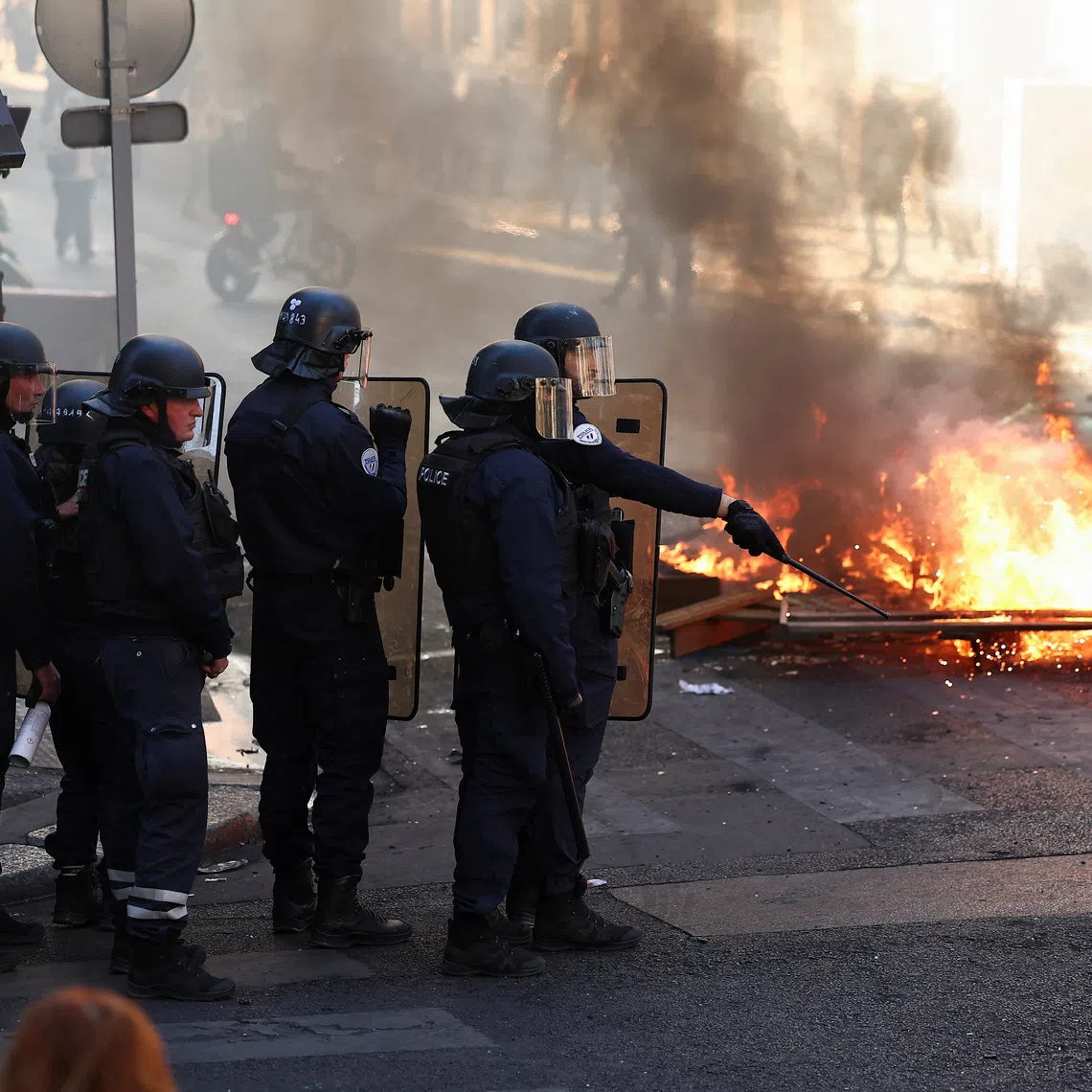 Police officers in riot gear stand near burning fire, in Paris, France, October 18, 2026. REUTERS/Abdul Saboor