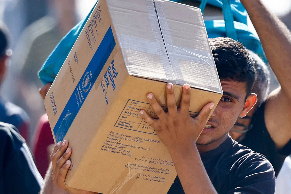 A Palestinian carries aid supplies that entered Gaza, amid a ceasefire between Israel and Hamas in Gaza, in Zawaida in the central Gaza Strip. REUTERS/Mahmoud Issa