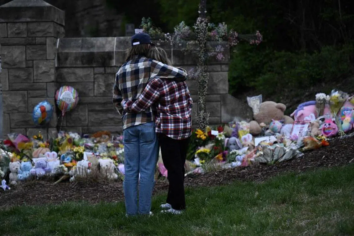 A couple pay their respects at a makeshift memorial for victims at the Covenant School building at the Covenant Presbyterian Church following a shooting, in Nashville, Tennessee, on March 28, 2023. 